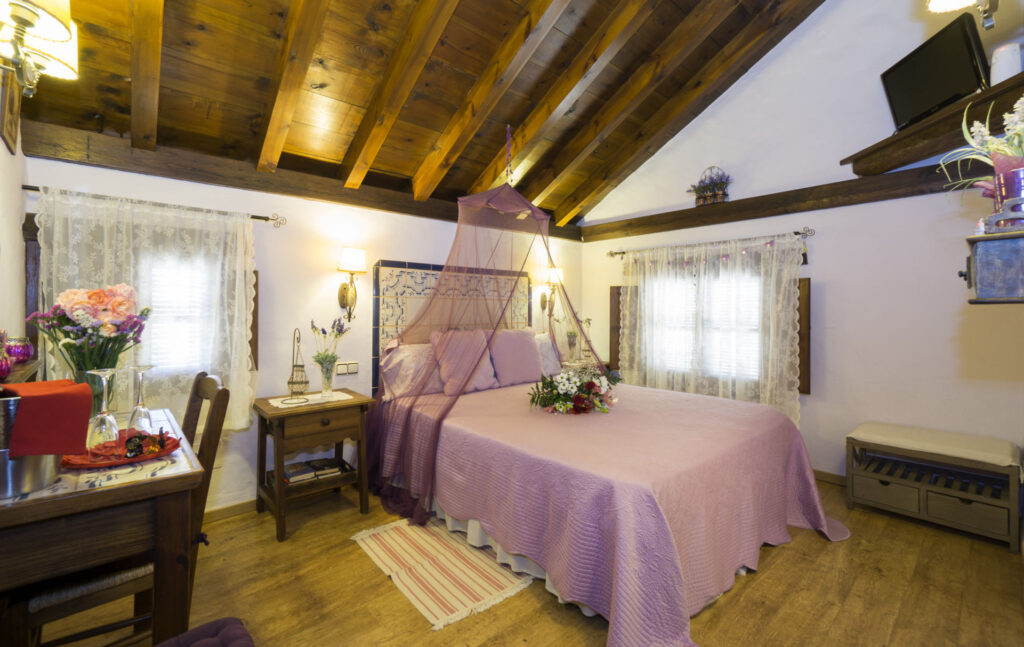 Vista general de la habitación Lavanda Romántica, con cama con dosel y velo, ramo de flores sobre la cama y mobiliario