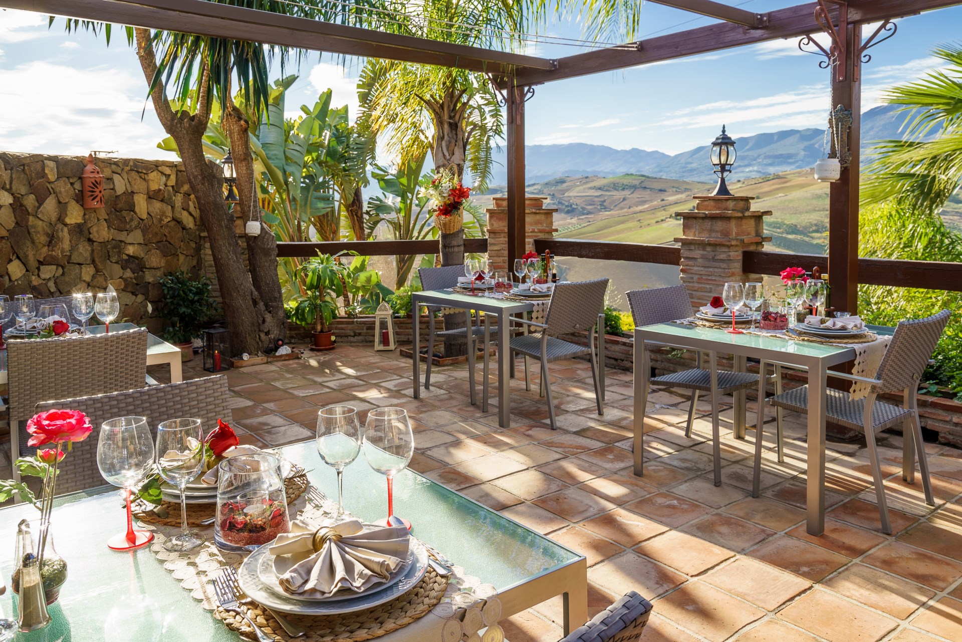 Terraza al aire libre con varias mesas del restaurante montadas con todo lujo de detalles, impresionantes vistas del valle al fondo