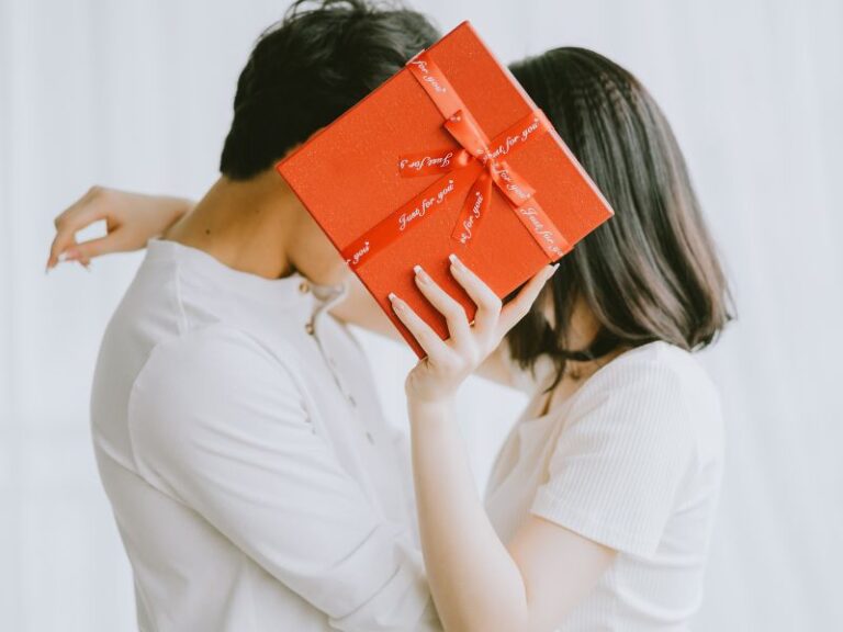 Pareja en pose romántica tras una caja de regalo