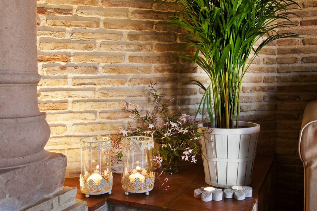 Detalle de mesa con velas y planta dentro de la habitación Jazmín SPA Exclusive, junto a una columna antigua